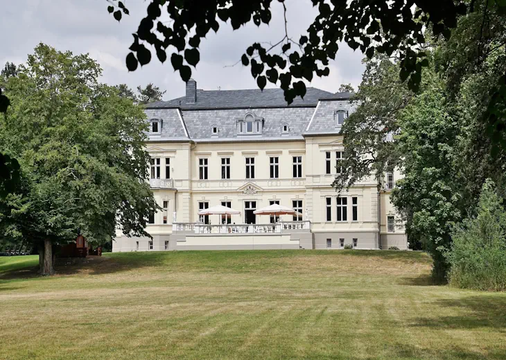 Blick durch den Schlosspark auf die Terrasse des Eventschlosses Schönfeld