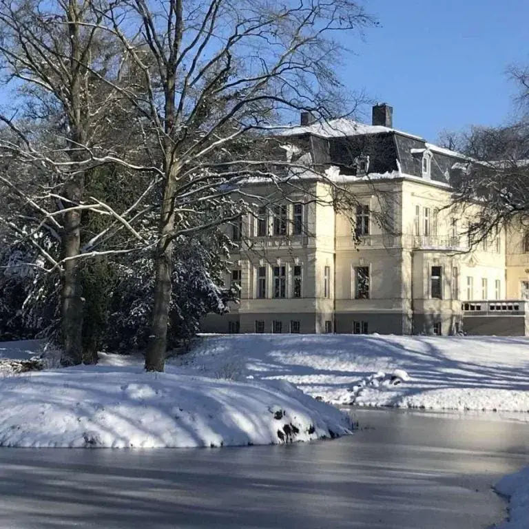 Winterlicher Blick über den See auf das verschneite Eventschloss Schönfeld – romantische Kulisse für Hochzeiten
